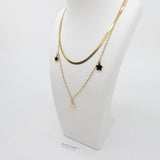 Close-up of the Twilight Stars Necklace showing fine details of the black and white enamel star charms on an 18K gold plated titanium steel chain. The stars have a smooth, glossy finish that contrasts beautifully against the gold.