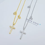 Close-up of the Mini Grace Necklace showcasing the polished sterling silver cross pendant, with a delicate CZ heart charm and a tiny star charm dangling asymmetrically on either side. The craftsmanship highlights shine, detail, and delicate proportions.