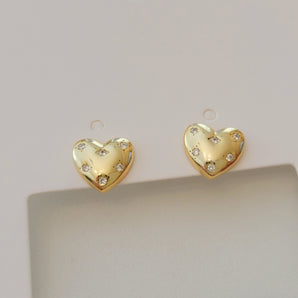Close-up of the Starry Heart Studs showcasing their sculpted heart shape in polished 925 sterling silver. The electroplated finish enhances their high-shine, reflective surface, while the design captures modern elegance with a hint of playful boldness. Weight and metal texture clearly visible.