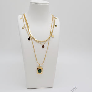 Close-up of the Triple Layers Emerald Necklace featuring three gold electroplated chains with emerald-colored charm detailing. Each layer offers a distinct look while maintaining an elegant and cohesive design.