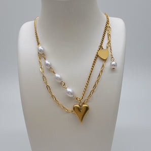 Close-up of Heart Dangling Pearl Layers Necklace showing dual-layer gold chain with a dainty heart charm and pearl drop. Electroplated titanium steel reflects a polished gold finish with elegant detailing.