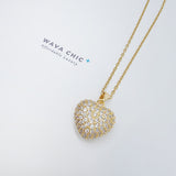 Close-up of the Apple Heart Necklace showing a heart-shaped pendant designed like an apple, paved with sparkling cubic zirconia stones. The pendant has a smooth 18K gold-plated finish, and it hangs from a sleek stainless steel chain. Crafted for durability and glamour.