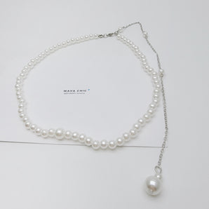 Close-up of the Gracefall Pearl Necklace showing a strand of radiant imitation pearls cascading from a gold-toned copper chain. The rich luster and bold design offer a luxurious, high-impact look perfect for dressing up any outfit.