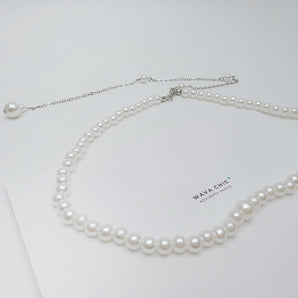 Close-up of the Gracefall Pearl Necklace showing a strand of radiant imitation pearls cascading from a gold-toned copper chain. The rich luster and bold design offer a luxurious, high-impact look perfect for dressing up any outfit.